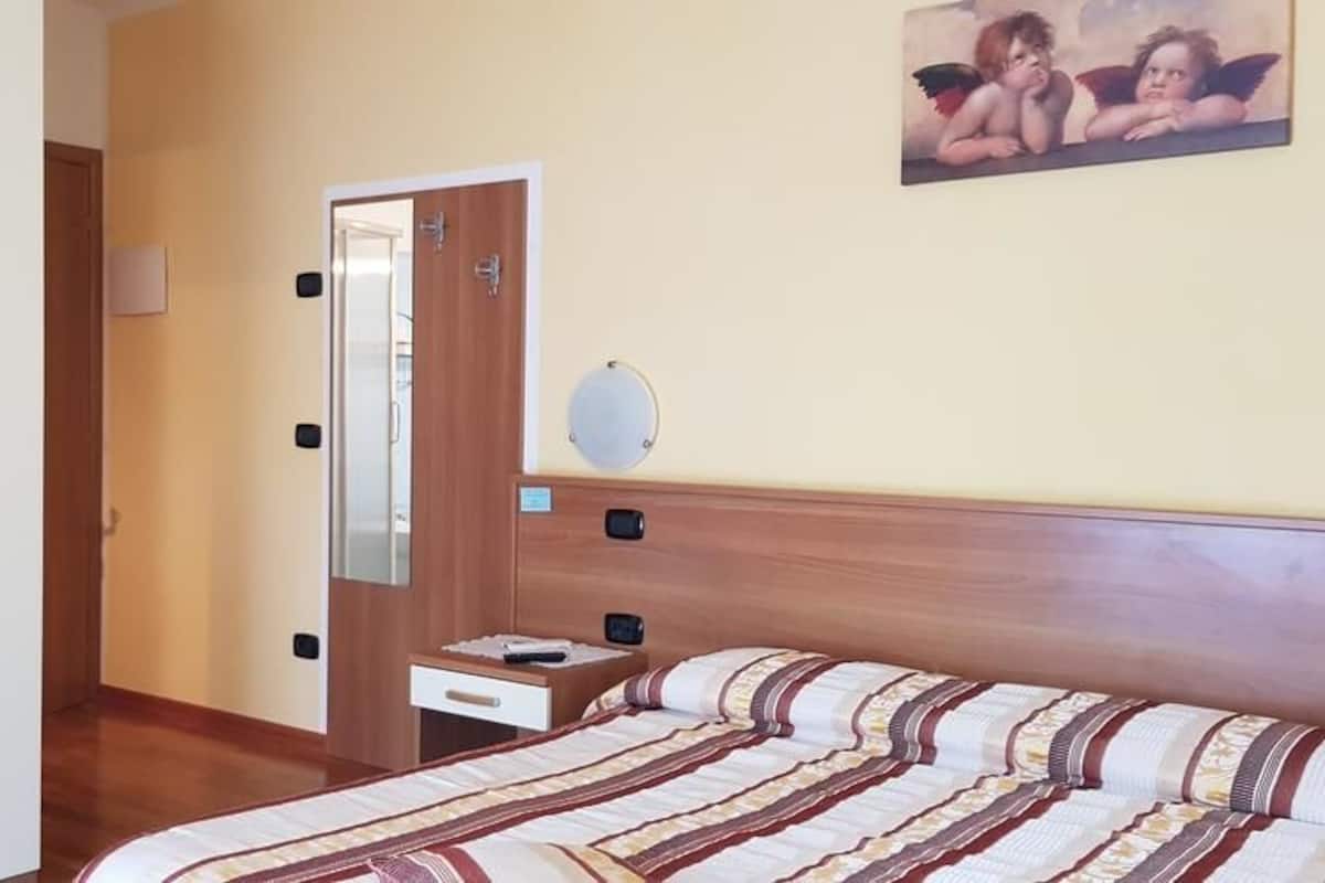 Un dormitorio con cama, mesita de noche, espejo y armario.