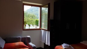 Una camera da letto con un'ampia finestra, un armadio e un letto con coperta rossa.