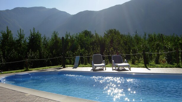 Piscina con due sdraio di fronte a uno sfondo montuoso.