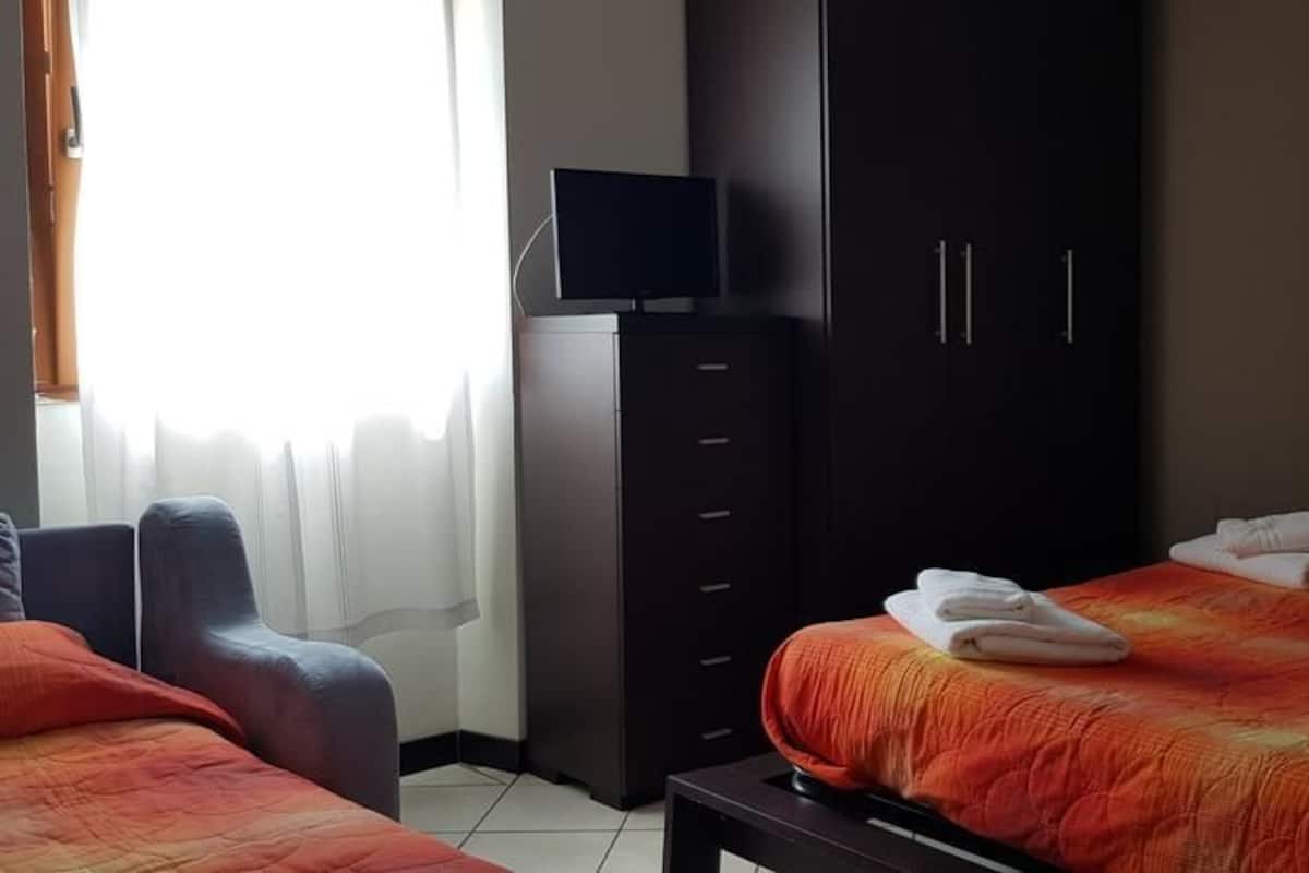 Habitación triple, balcón, vista a la montaña | Edredón, caja de seguridad en la habitación y escritorio