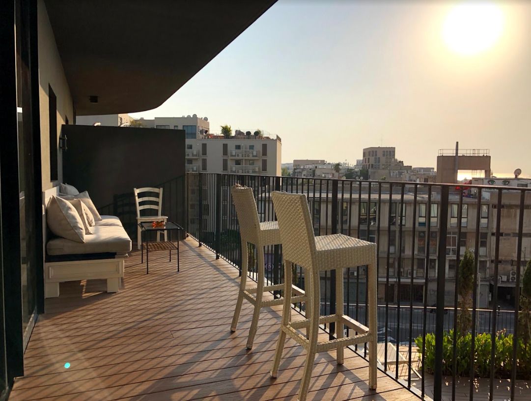 A balcony with a sofa, two chairs, and a small table.