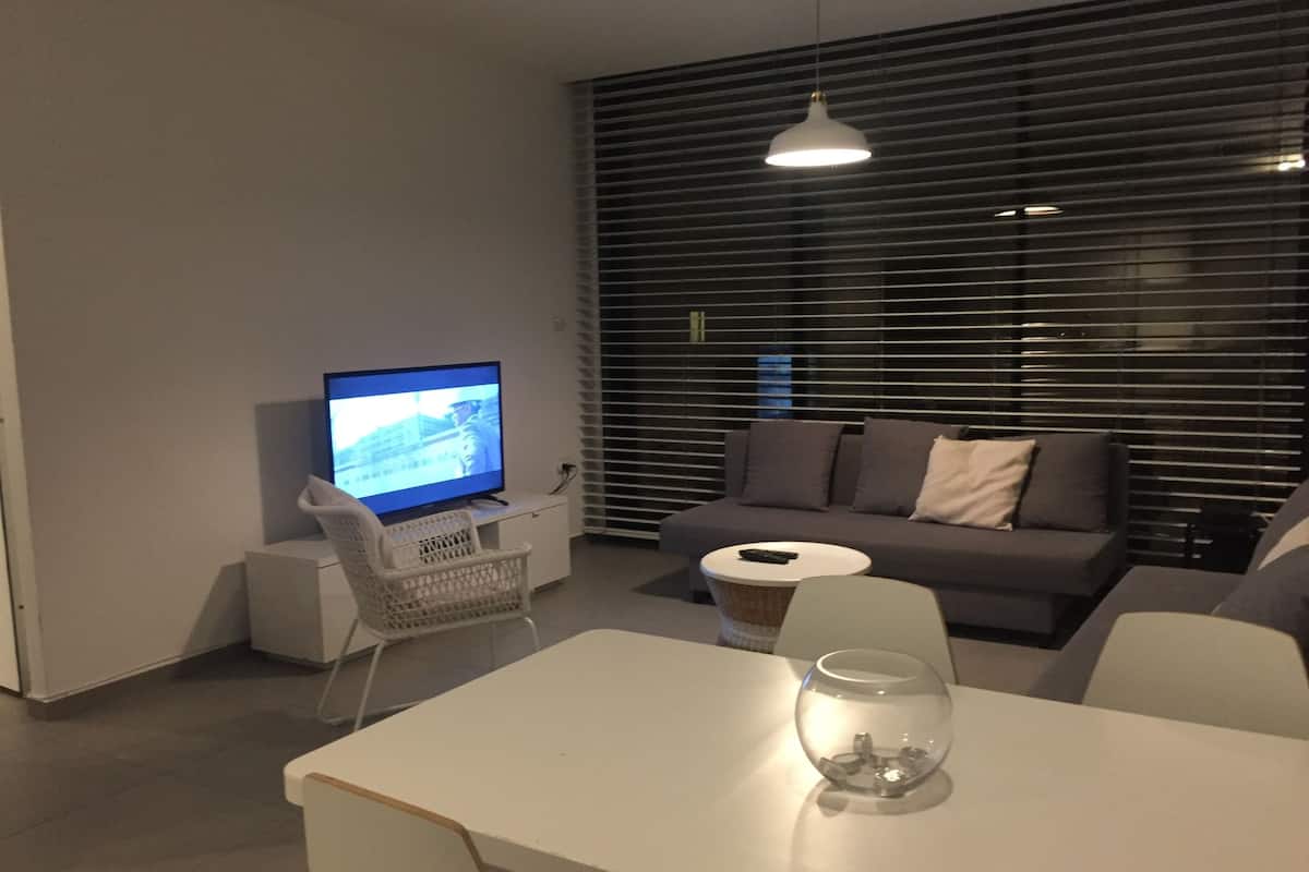 A modern living room with a television, sofa, and a glass fishbowl on a table.
