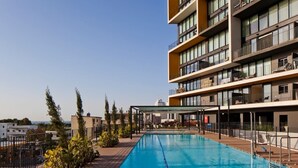 A modern hotel with a rooftop swimming pool, multiple balconies, and a view of the cityscape. - Elifelet 26 (Tel Aviv)