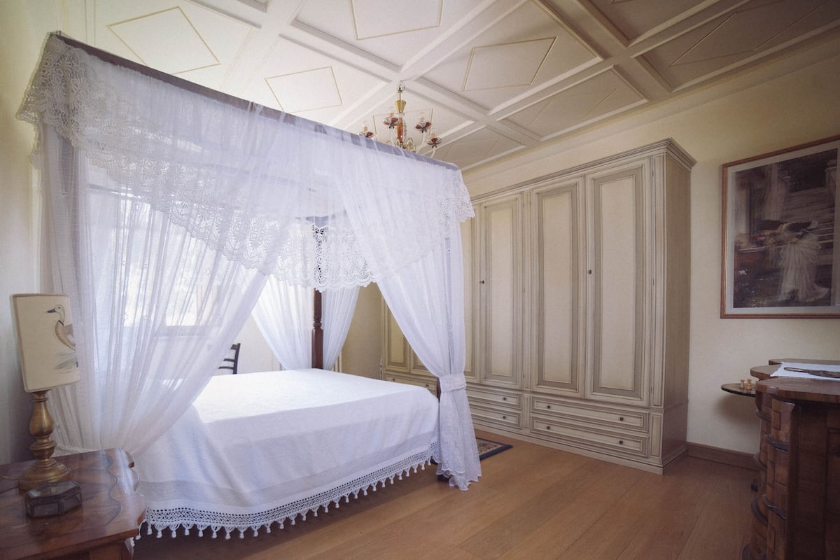 Un dormitorio con cama con dosel, armario de madera y un cuadro en la pared.