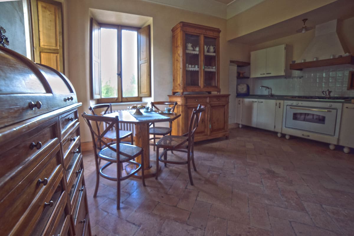 Una cocina con mesa, sillas, armarios de madera y estufa.