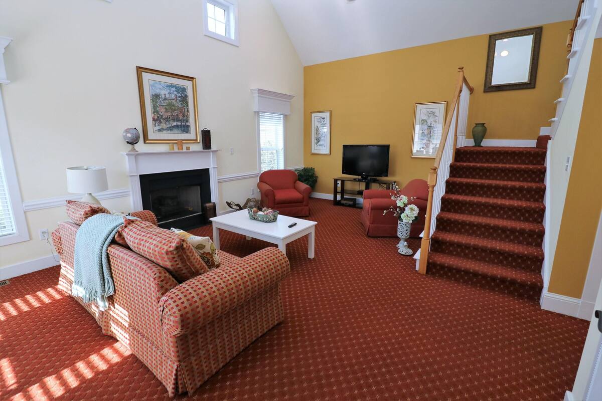 A living room with a fireplace, a television, and a staircase.
