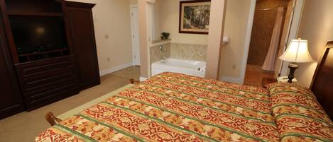 Un dormitorio con una cama grande, televisión, bañera y ducha.