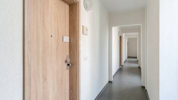 A hallway with a wooden door, a light switch, and a wall-mounted light fixture.