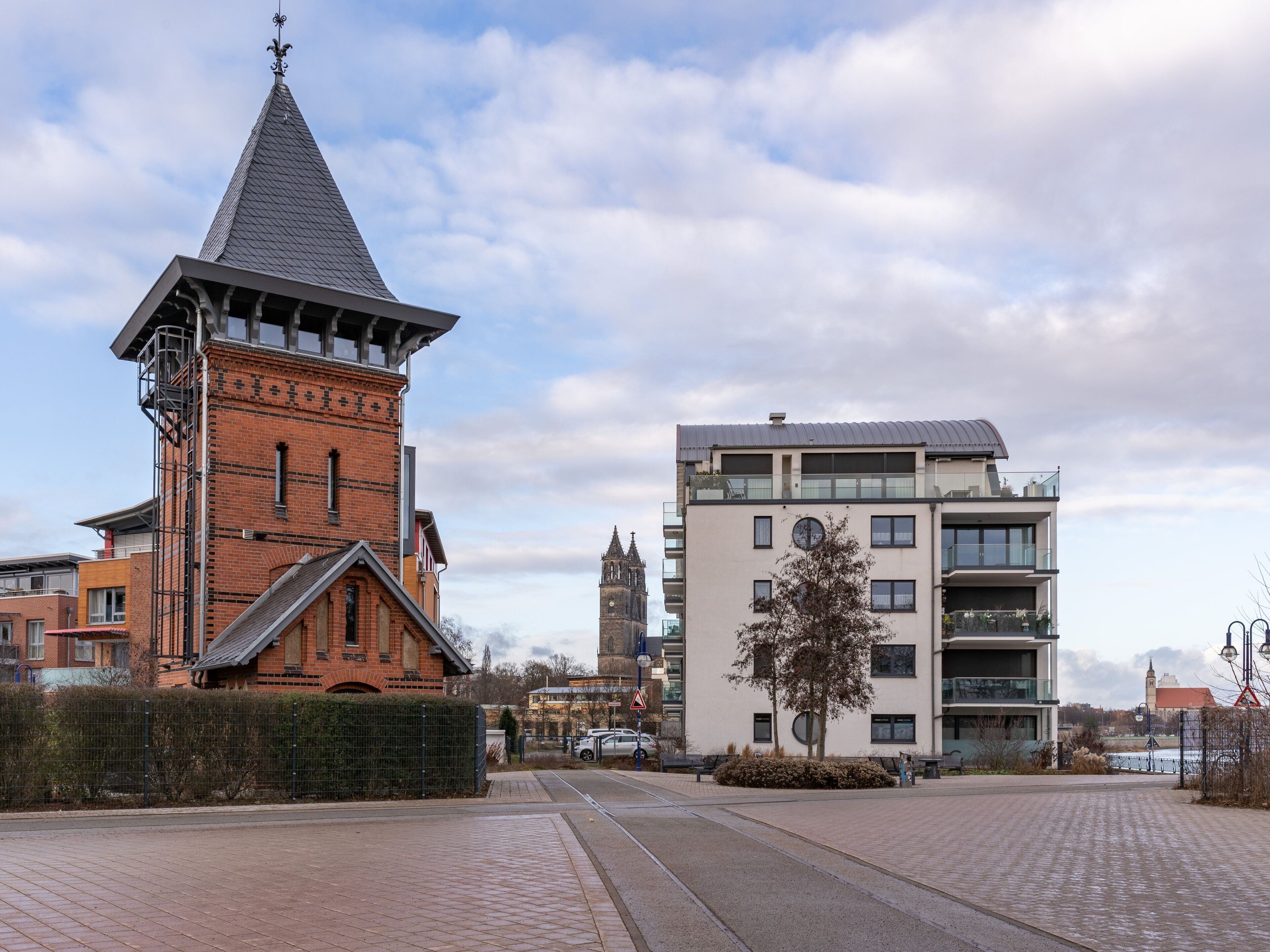 Eine Kirche mit einem hohen Kirchturm und ein modernes Gebäude mit großen Fenstern und Balkonen.