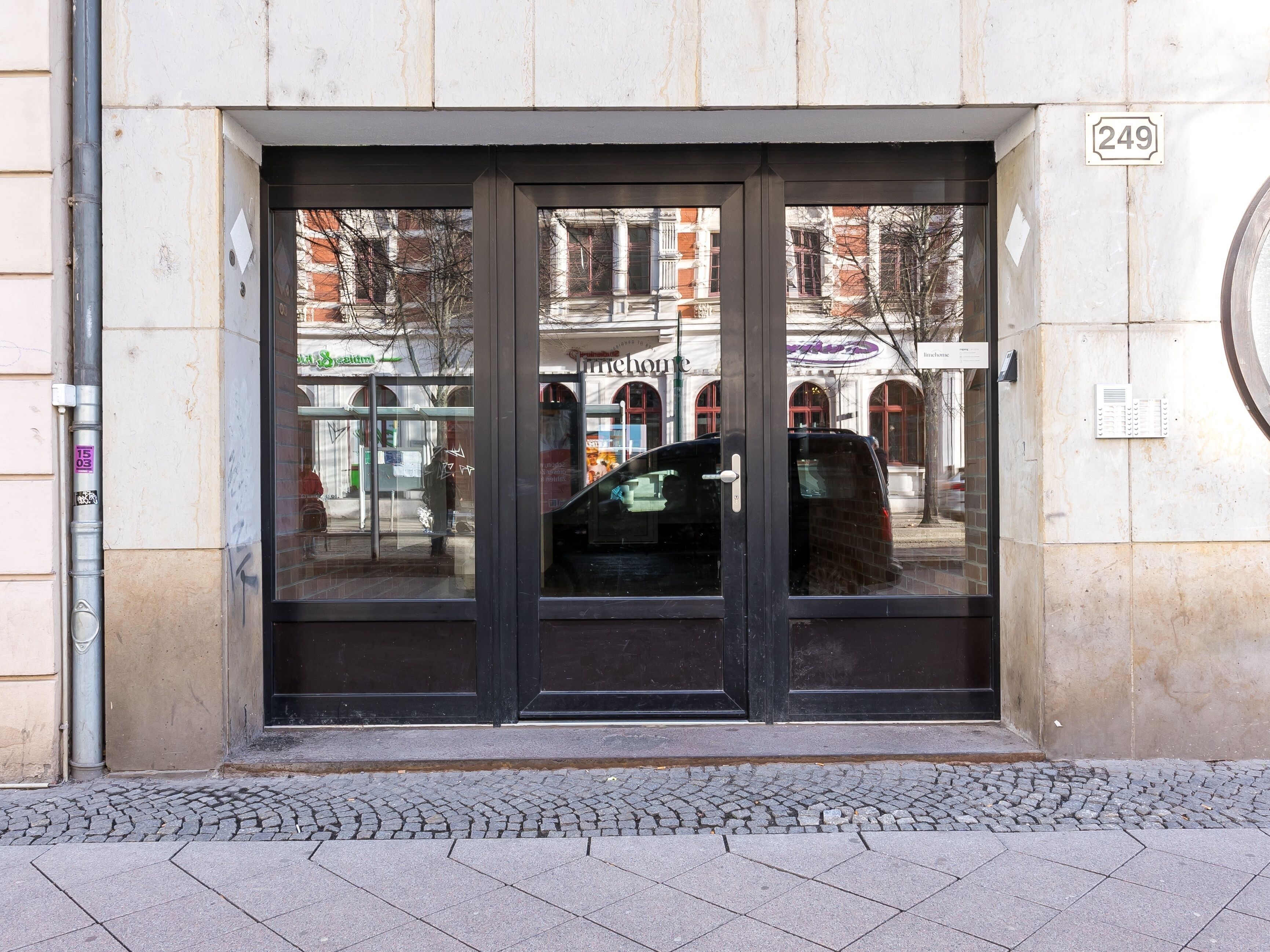 A building entrance with a glass door, a number '249' sign, and a cobblestone pavement.
