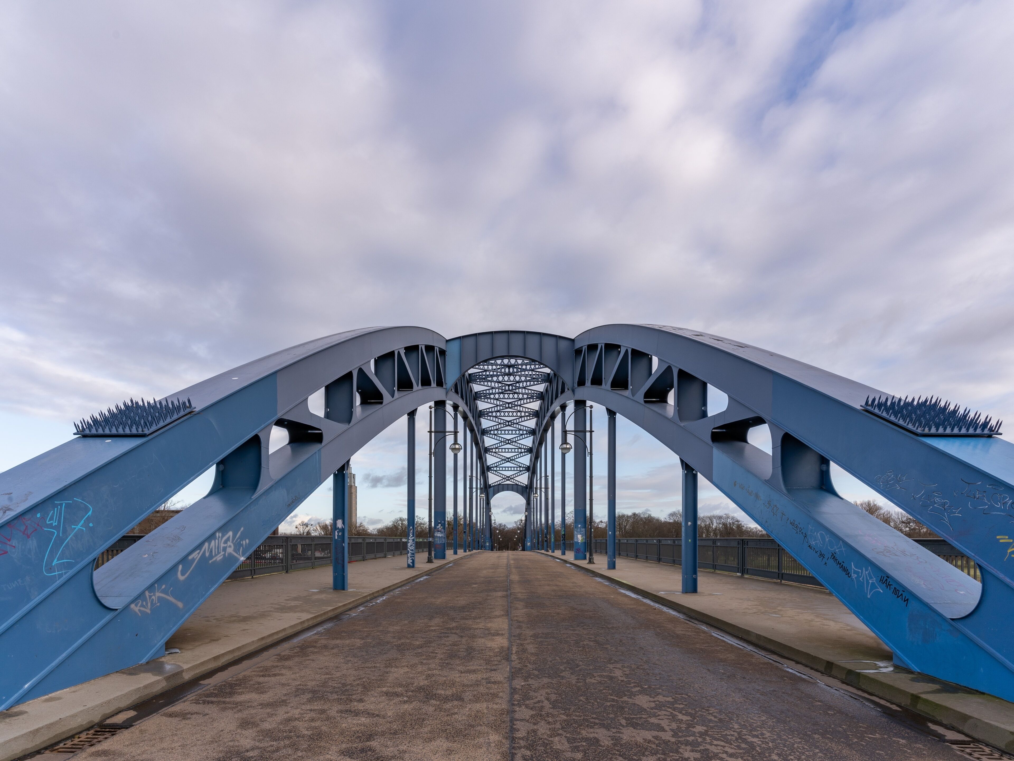 Un pont à la structure métallique, dont les côtés sont recouverts de graffitis.