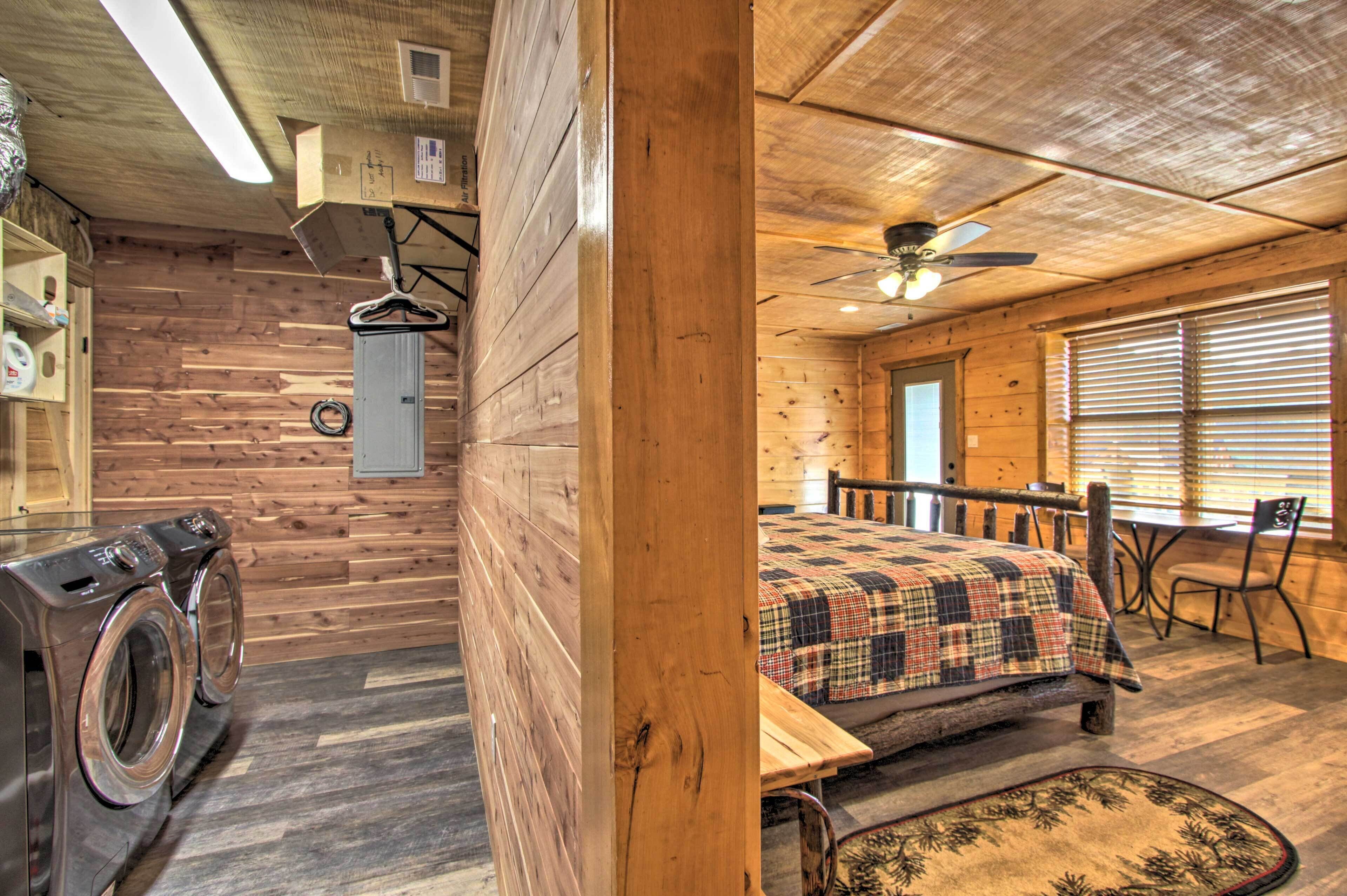 Interior de una cabaña de madera con una cama, una mesa y un ventilador de techo.