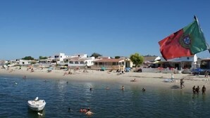 En strand med folk som badar och en flagga i bakgrunden.