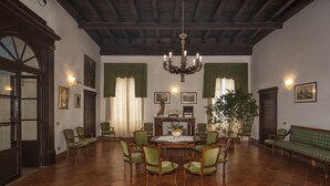 Zona pranzo con un tavolo rotondo, sedie, un lampadario e un divano verde.