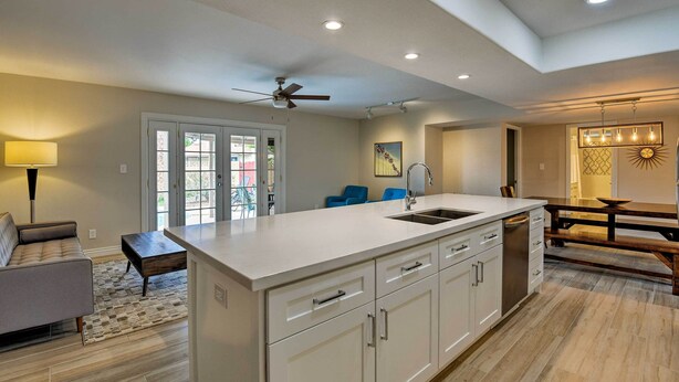 A modern kitchen with white cabinetry, a central island, and a ceiling fan. - 3 Mi to ASU: Tempe Getaway w/ Heated Pool (Tempe)