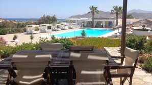 A poolside area with lounge chairs and a view of the sea and mountains.
