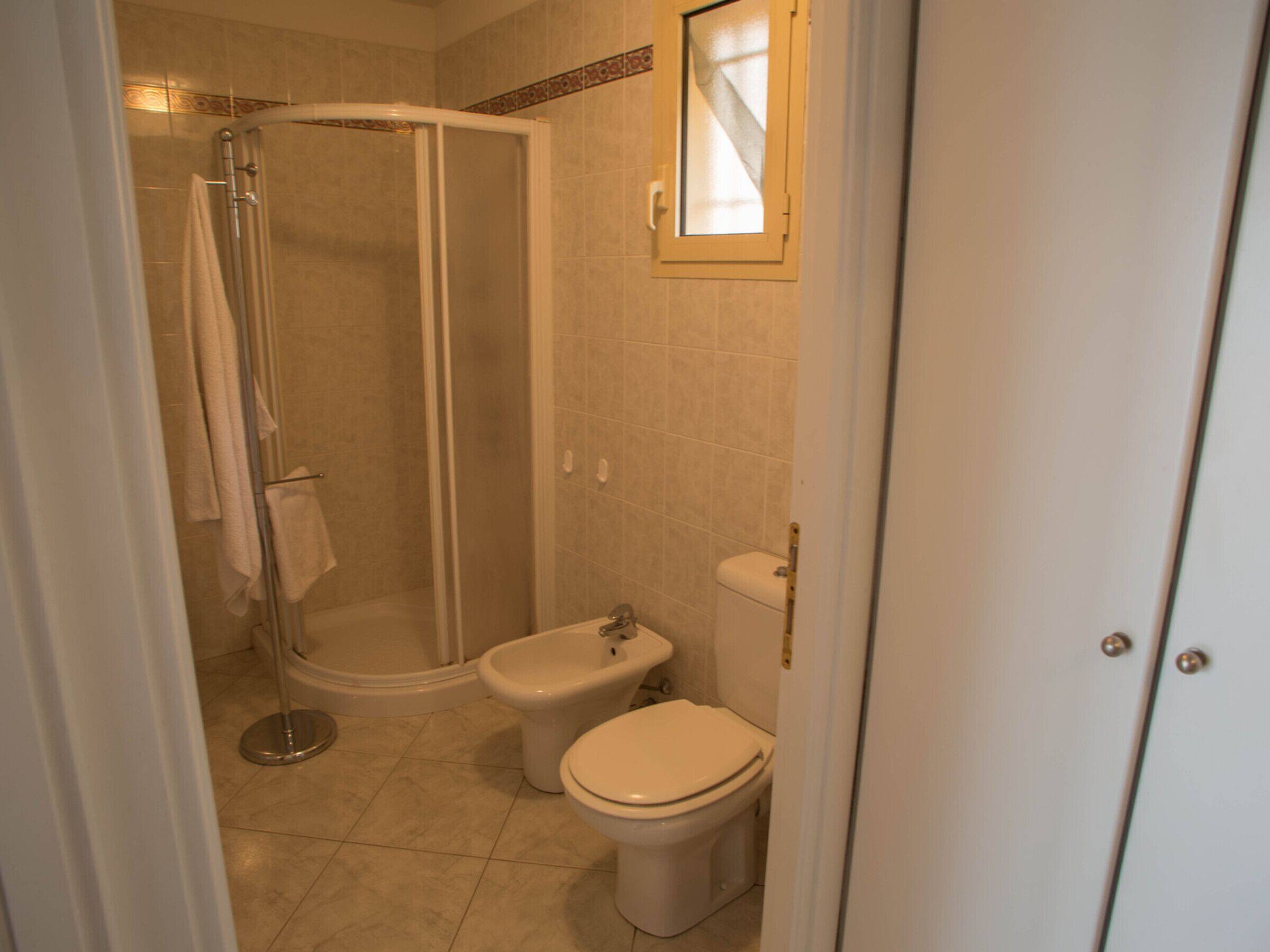 A bathroom with a shower, toilet, and bidet.