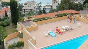 A rooftop pool area with lounge chairs and a view of the sea and buildings. - Cozy 2BR with terrace, pool, and garage (Menton)