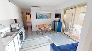A modern kitchen with a dining area, a sofa, and a TV. - Cozy 2BR with terrace, pool, and garage (Menton)