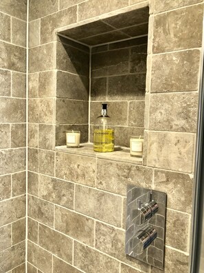 A bathroom with stone tiles, a soap dispenser, and a hand soap bottle. - Stylish Maisonette and studio in Victoria (London)