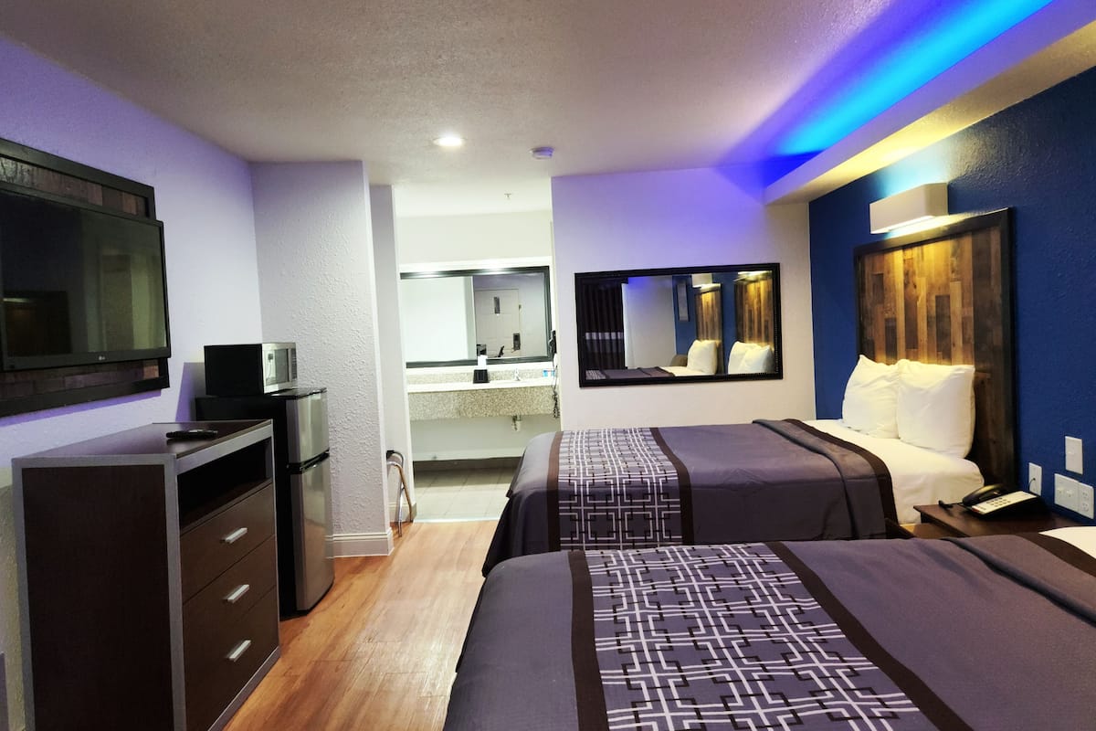 A hotel room with a bed, bedside table, TV, and a mirror.