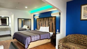A hotel room with a bed, a sofa, a desk, and a mirror.