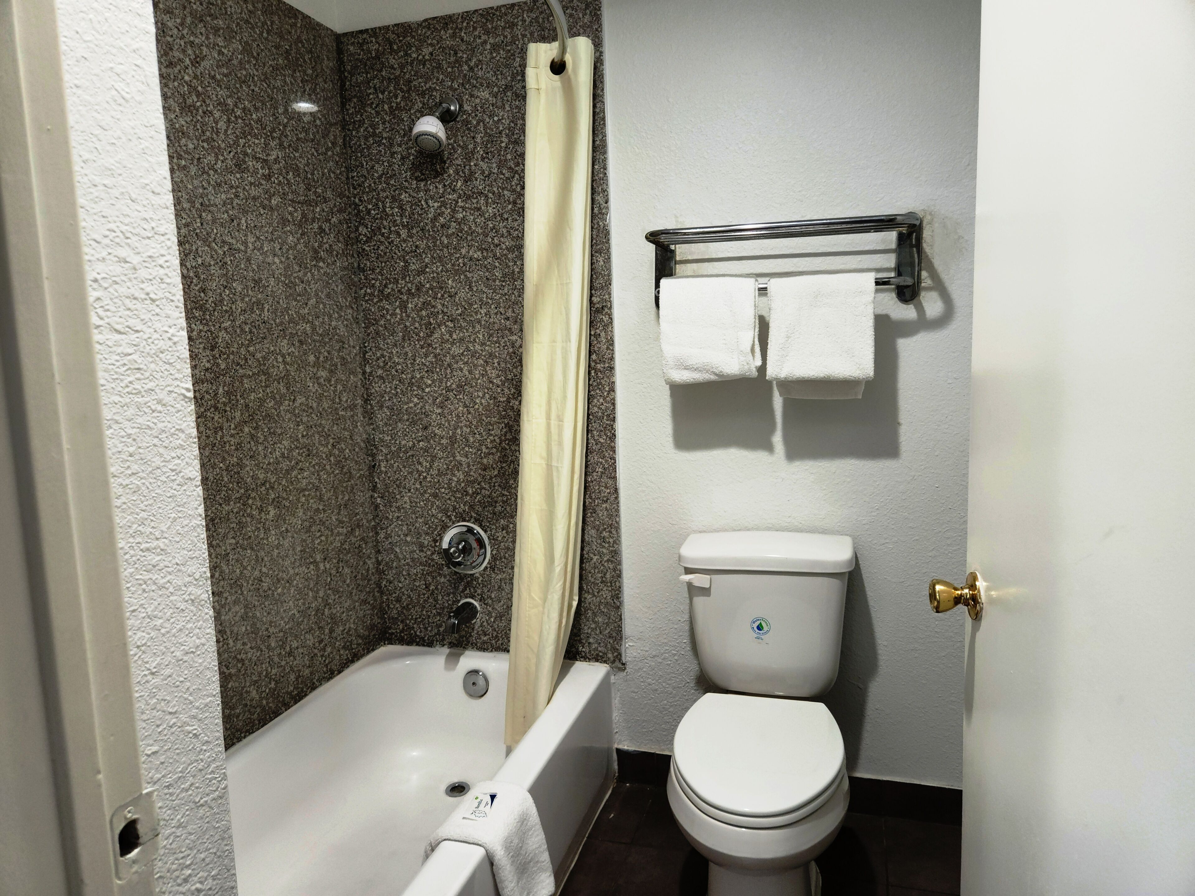 Une salle de bain équipée d’une baignoire, d’une douche, de toilettes et d’un porte-serviettes.