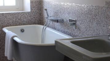 A bathroom with a clawfoot bathtub, a sink, and a window.