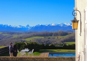 Terraço com mesa e cadeiras com vista para uma paisagem montanhosa.