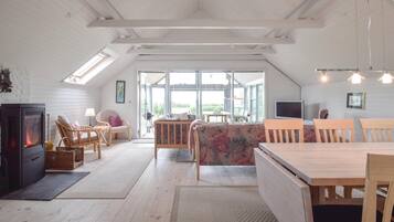 Une pièce confortable de style loft, dotée d’une cheminée, de meubles en bois et de grandes fenêtres offrant une vue sur l’extérieur.