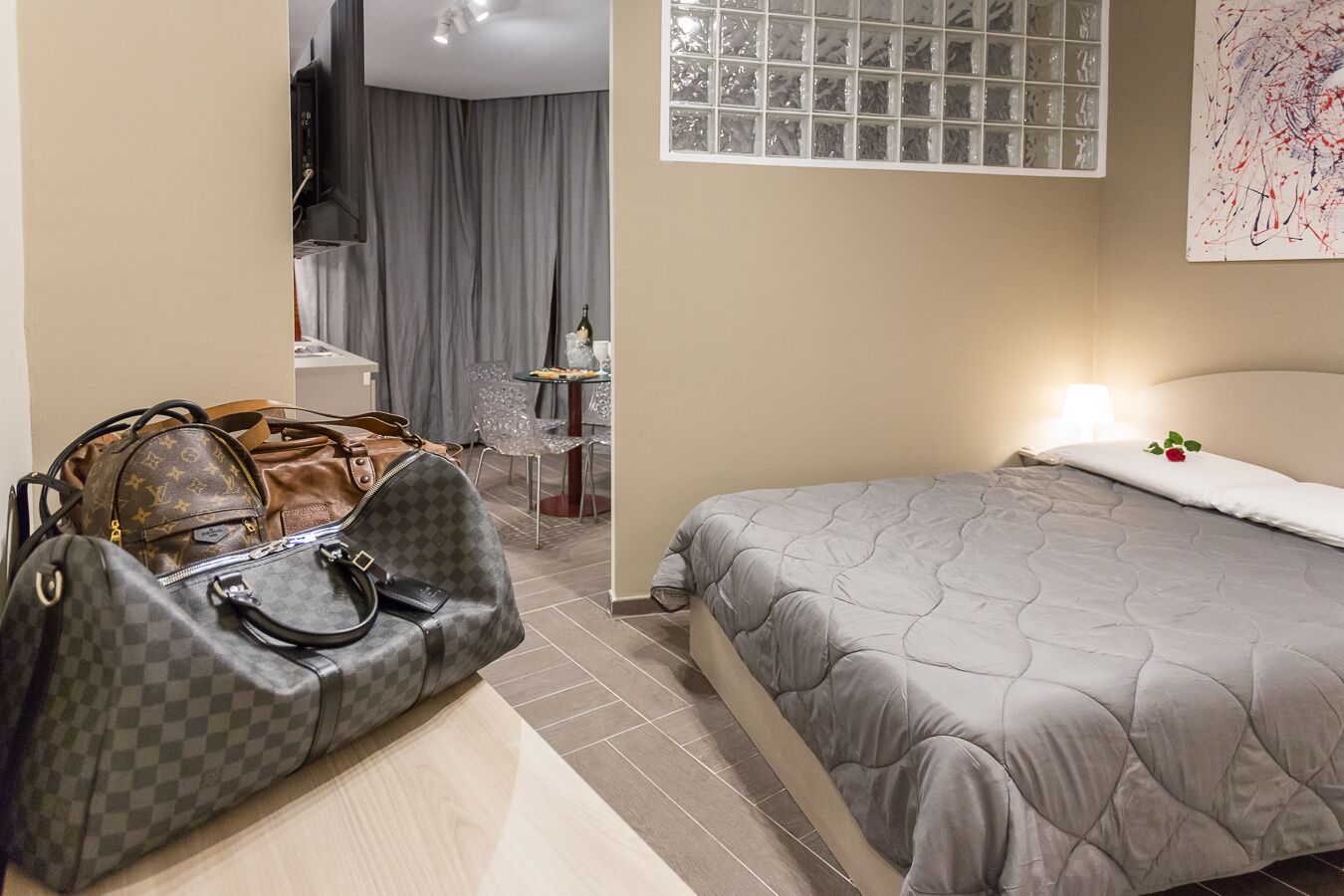 Una habitación de hotel con una cama, un escritorio, una silla y dos bolsos en el suelo.