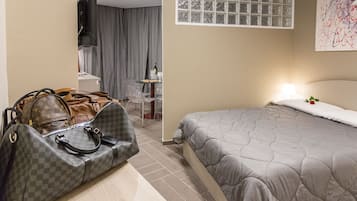 Una habitación de hotel con una cama, un escritorio, una silla y dos bolsos en el suelo.