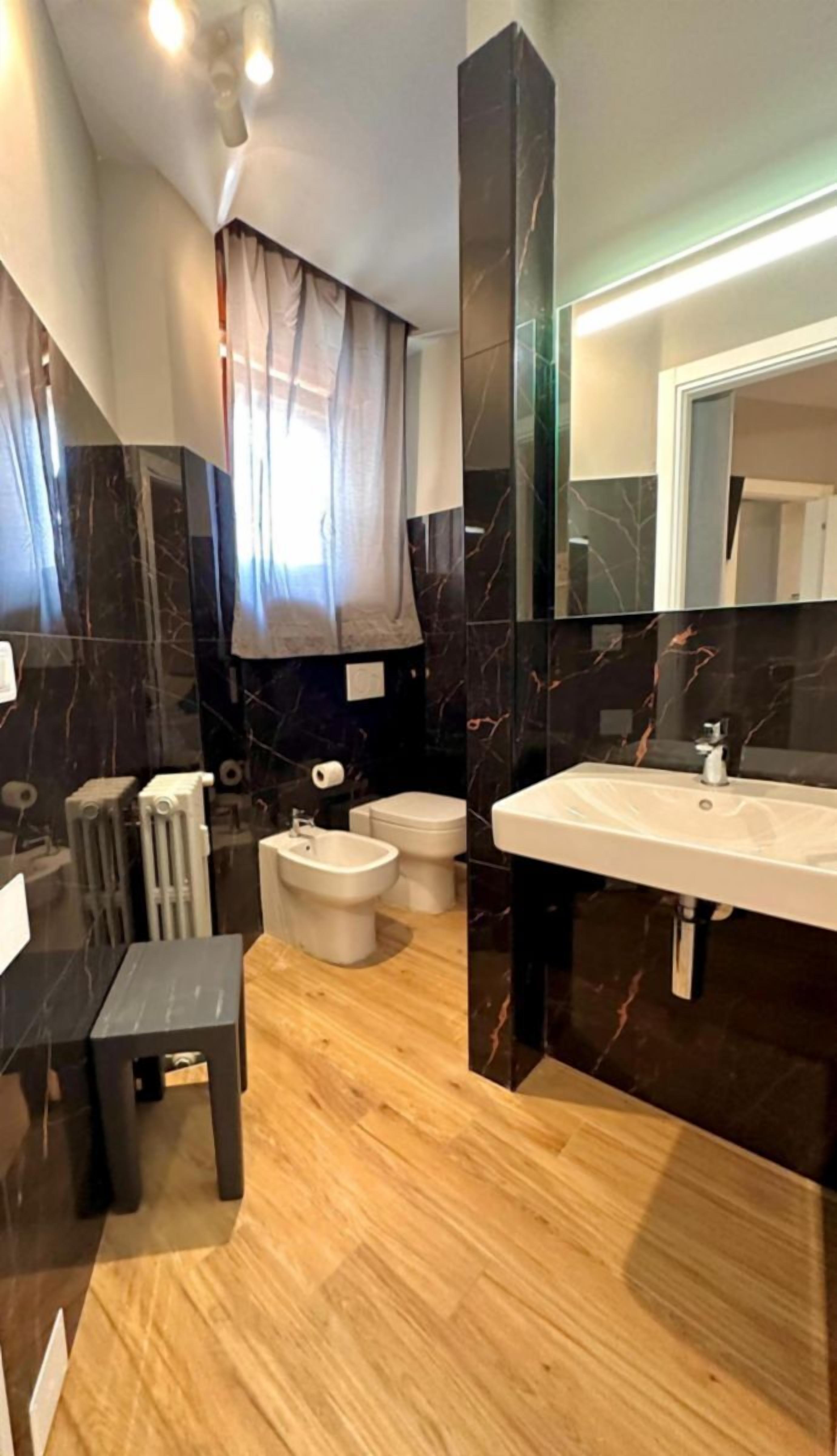 Ein modernes Badezimmer mit Marmor-Waschtisch, einem Bidet, einer Toilette und einem Heizkörper.