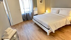 Habitación de hotel con cama, mesita de noche con lámpara, aire acondicionado de pared y ventana con cortinas.