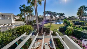 A pool area with palm trees, a clear sky, and a view of surrounding buildings. - Bungalow rental in Calpe, MARGARET (Calpe)