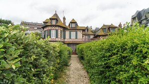 Ein traditionelles Gebäude im Tudor-Stil mit einem Kiesweg, der zum Eingang führt, umgeben von gepflegten Hecken.
