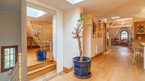 Ein geräumiges Zimmer mit Holzboden, einem Oberlicht und einem großen Topfbaum.