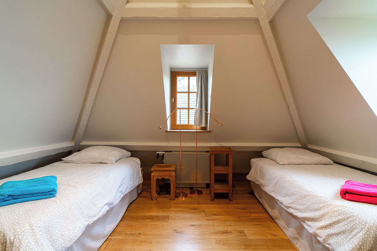 Ein kleines, gemütliches Schlafzimmer im Dachgeschoss mit zwei Betten, einem Fenster und einer Heizung.