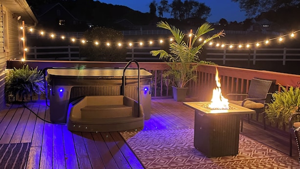 Une terrasse en bois avec un jacuzzi, un espace salon extérieur et un foyer.