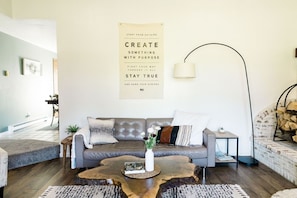 Un salon moderne avec un canapé gris, une table basse et une affiche motivante accrochée au mur.
