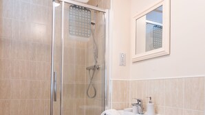 A bathroom with a glass-enclosed shower, a white sink, and a toilet. - Bladon Court (Basingstoke)