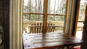 A wooden dining table with benches in a room with large windows and curtains. - Come SKI on the BEECH! Book your ski trip NOW, weekends going fast. (Beech Mountain)
