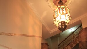 A staircase with mosaic tiles, a wooden handrail, and a hanging lantern. - Kasbah Imoula (Asni)