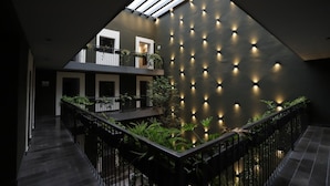 A modern interior with a sloped ceiling, a central garden area, and a series of lights on the wall.