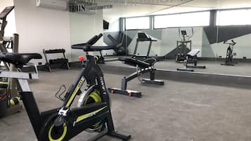 Ein Fitnessstudio mit Trainingsgeräten, darunter ein Ergometer und ein Laufband.