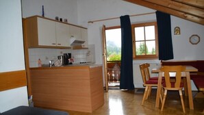 Une cuisine de taille réduite, dotée de meubles en bois et d’un coin repas avec une table et des chaises.
