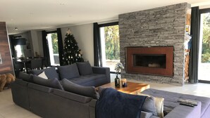 Una sala de estar moderna con un amplio sofá modular, una chimenea y un árbol de Navidad.