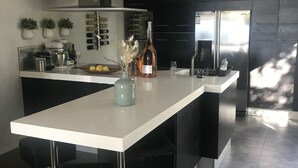 Una cocina moderna con una isla central, electrodomésticos de acero inoxidable y armarios negros.