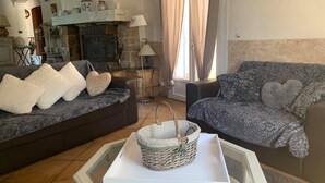 Uma sala de estar aconchegante com dois sofás, uma lareira e um cesto de vime sobre uma mesa de vidro.