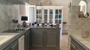 Cozinha moderna com armários cinza, uma ilha central e vista para a sala de jantar.